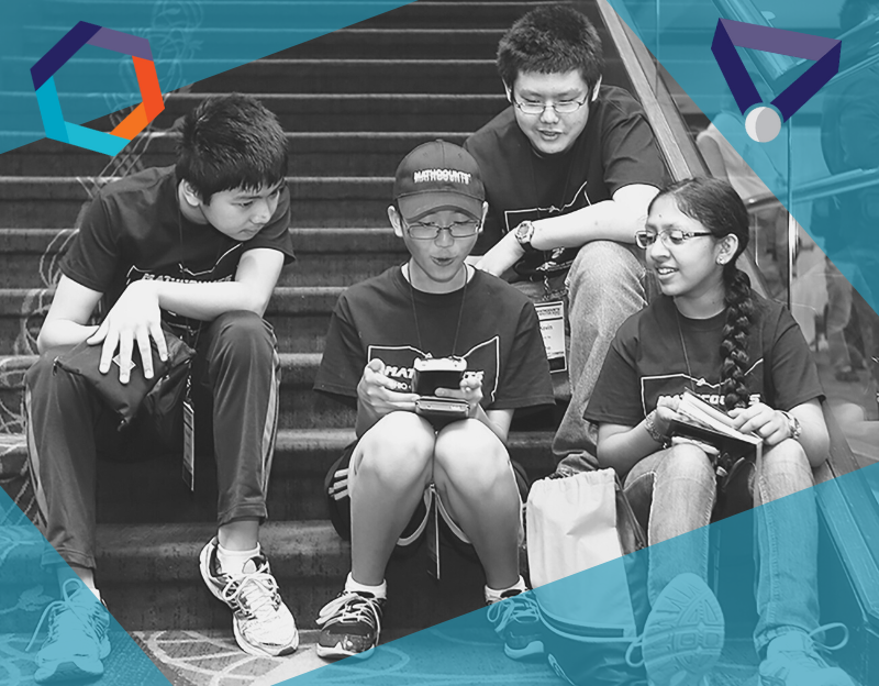 3 boys and a girl huddle around a calculator looking at it
